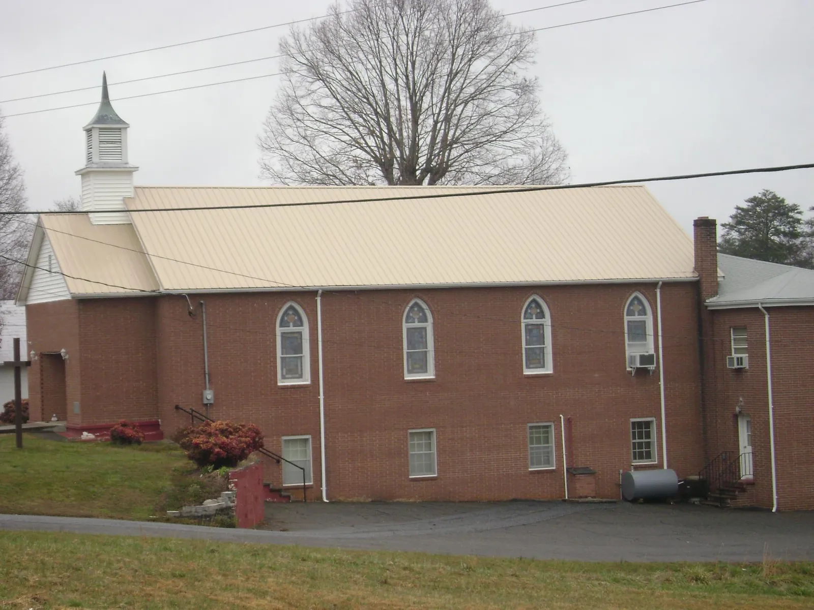 New tan metal roof on a brick church with a white steeple in Montezuma